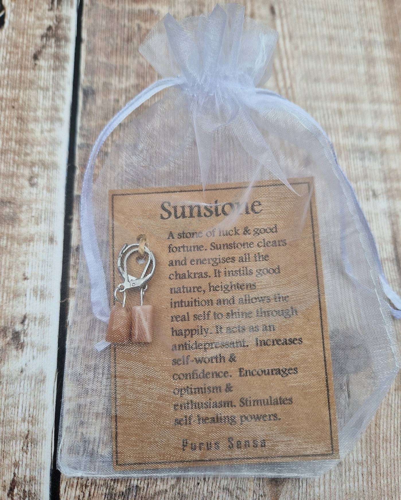 Natural sunstone huggie hoop crystal earrings on a descriptive card.