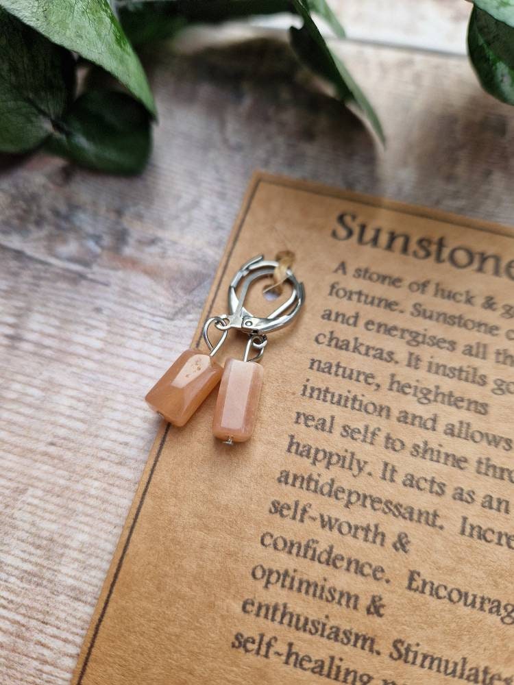 Natural sunstone huggie hoop crystal earrings on a descriptive card.