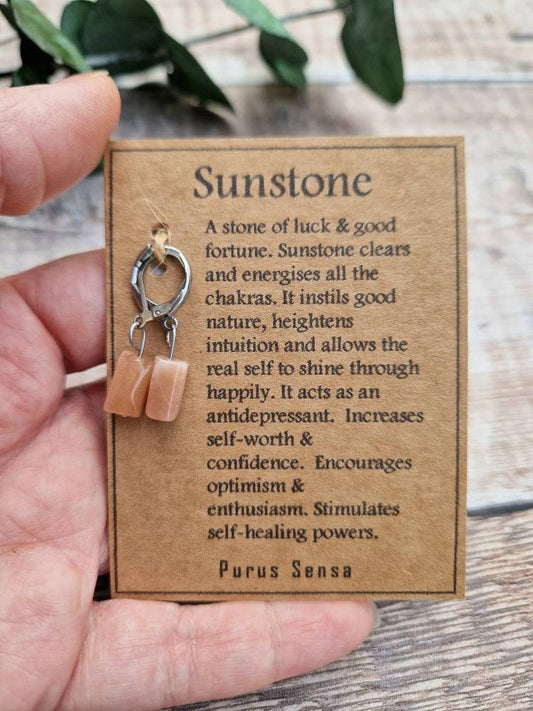 Natural sunstone huggie hoop crystal earrings on a descriptive card.